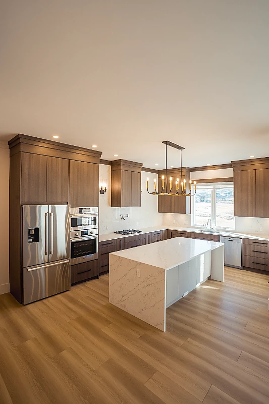 Custom kitchen with dark wood cabinets and a white waterfall island built by Double G Construction in Kamloops, BC