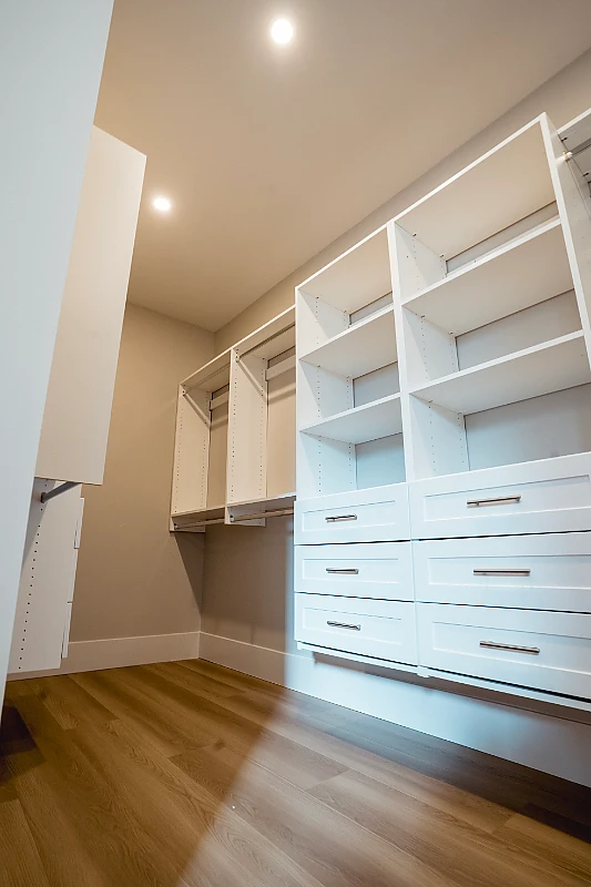 Custom white built-in shelving and drawers in a walk-in closet