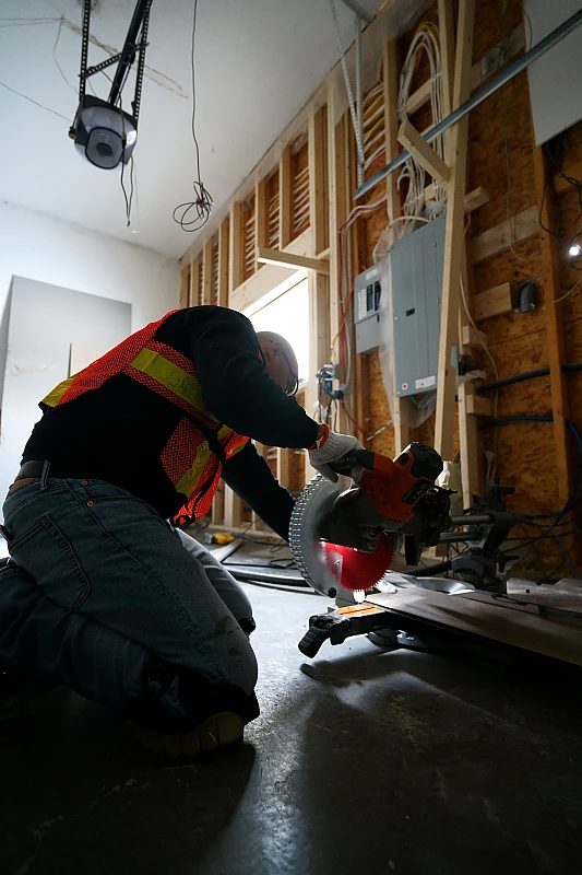 Cabinet installer using a mitre saw on site during a custom cabinetry installation