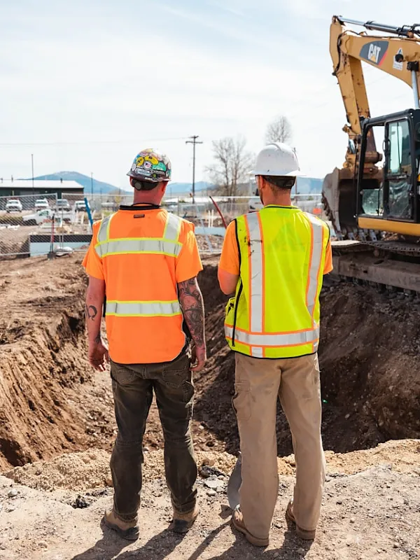 Double G Construction crew in hi-vis vests overseeing excavator work on a new home foundation excavation