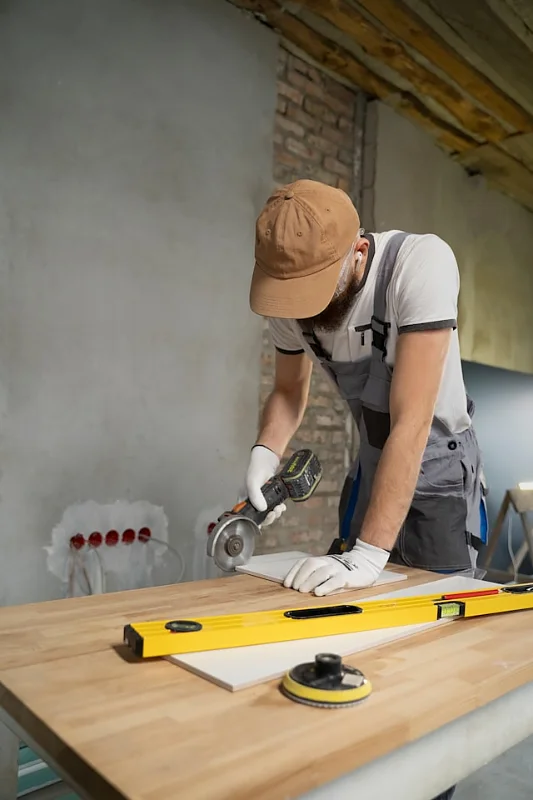 Renovation carpenter in work overalls cutting material on a workbench with a spirit level in the foreground
